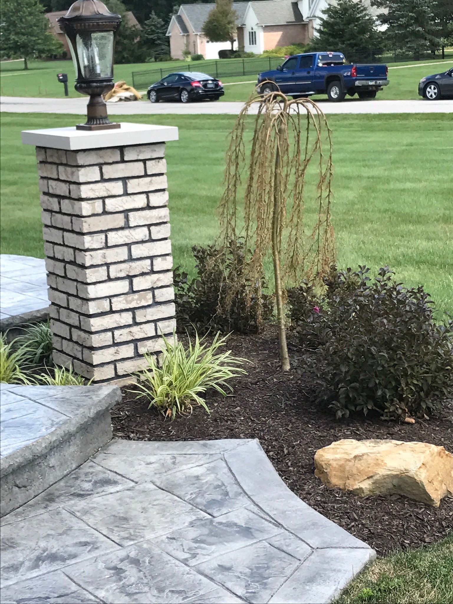 A brick pillar with a lamp on top of it in a yard.