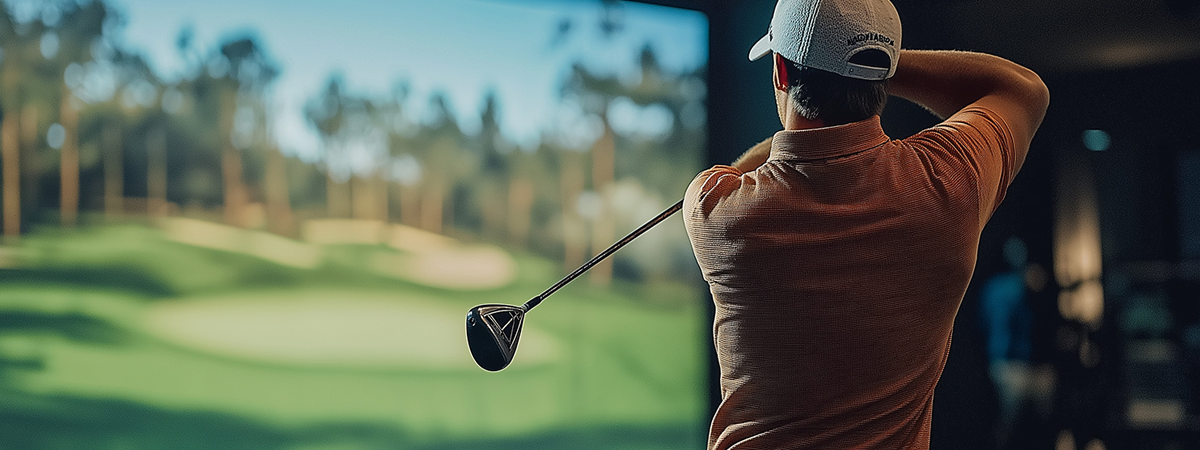 A man swings a golf club on a track man golf simulator