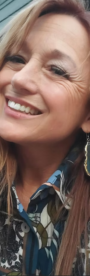 Woman smiling, wearing a patterned shirt and earrings.