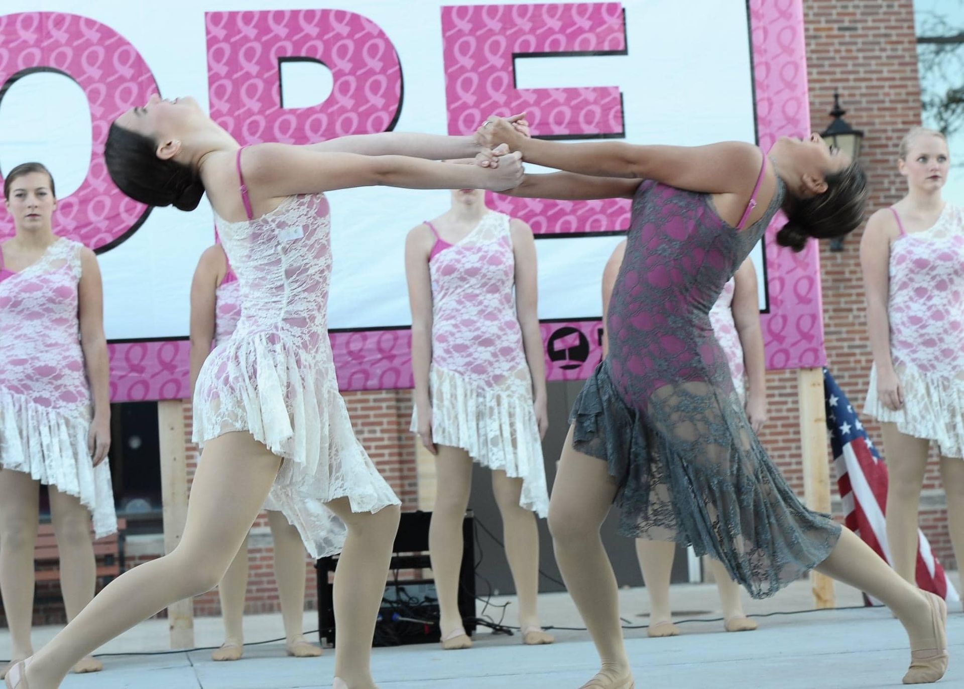 A group of women are dancing in front of a sign that says open