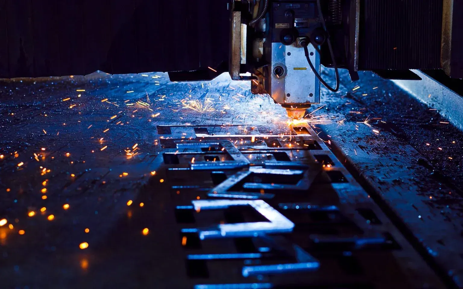 A machine is cutting a piece of metal with sparks coming out of it