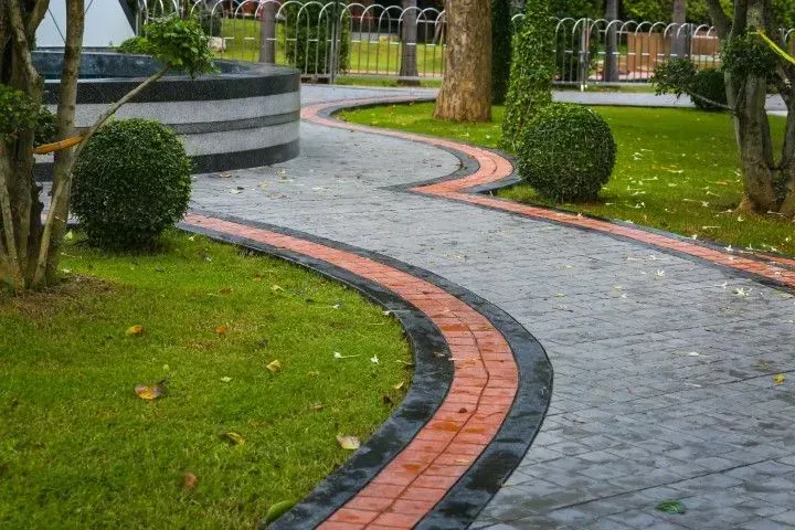 Curved stone garden path with red brick edging beside green grass and trees