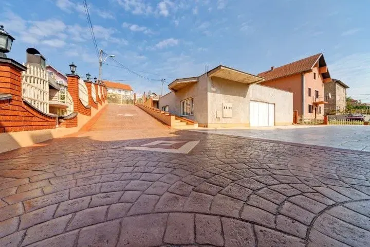 Sunlit cobblestone courtyard with houses, stairs, and a clear blue sky
