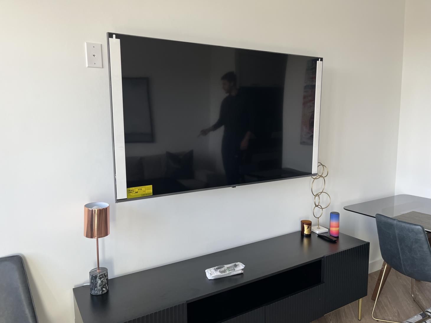 Hands securing a TV mount onto the wall, preparing to install a television.