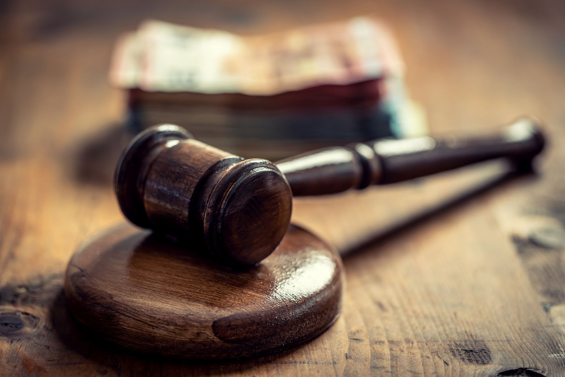 Judge's gavel resting on a wooden block with blurred currency notes in the background.