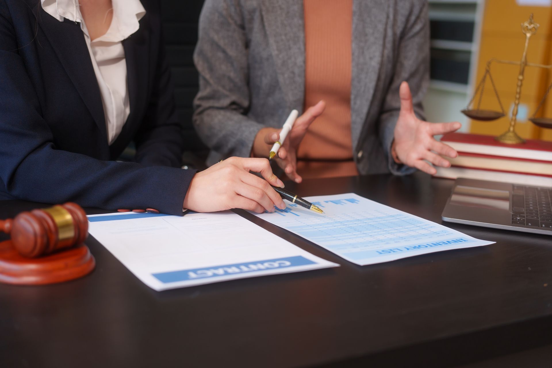 A close-up of two female lawyers' hands working at a desk, handling legal documents.