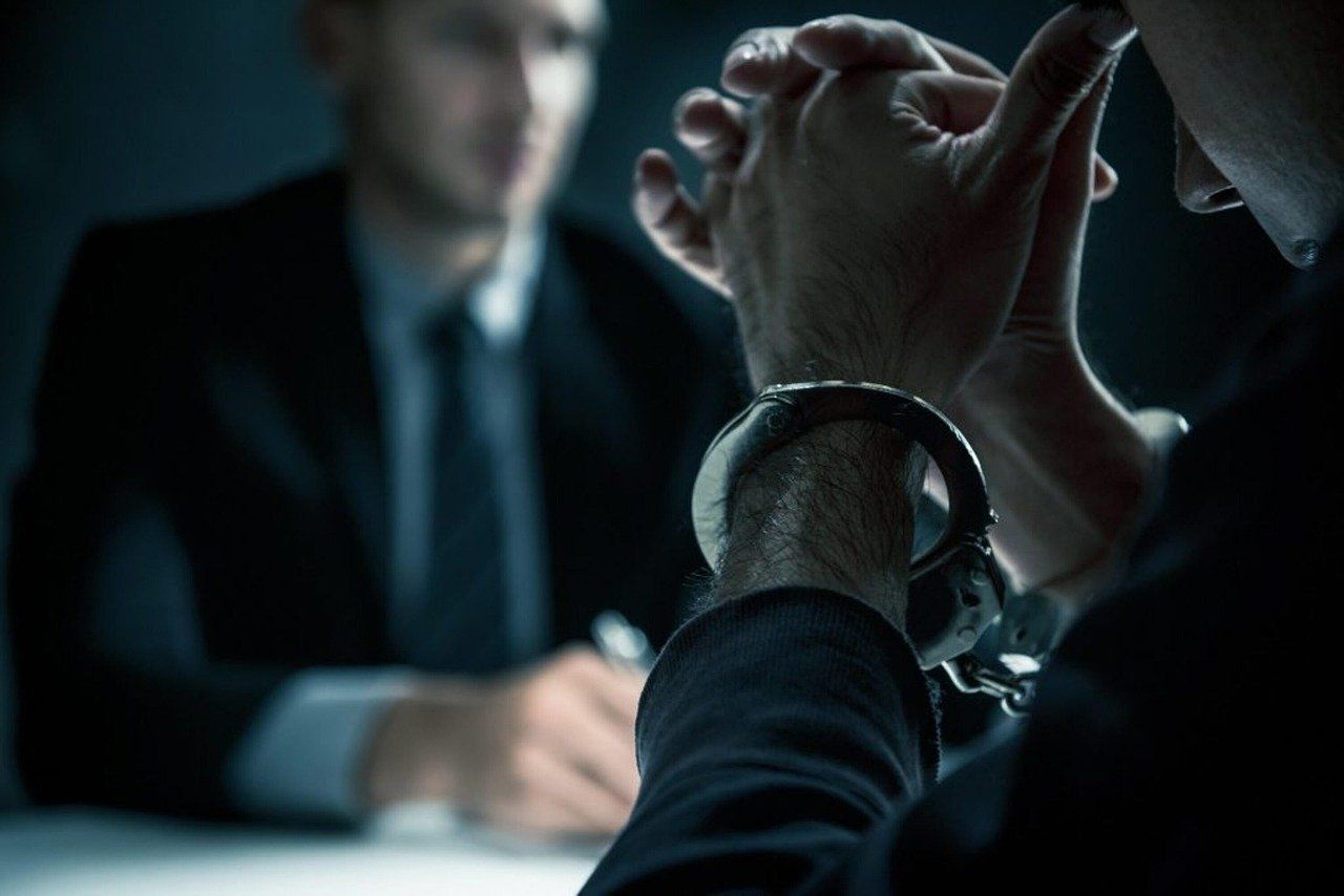 A man in handcuffs is sitting at a table with a man in a suit.