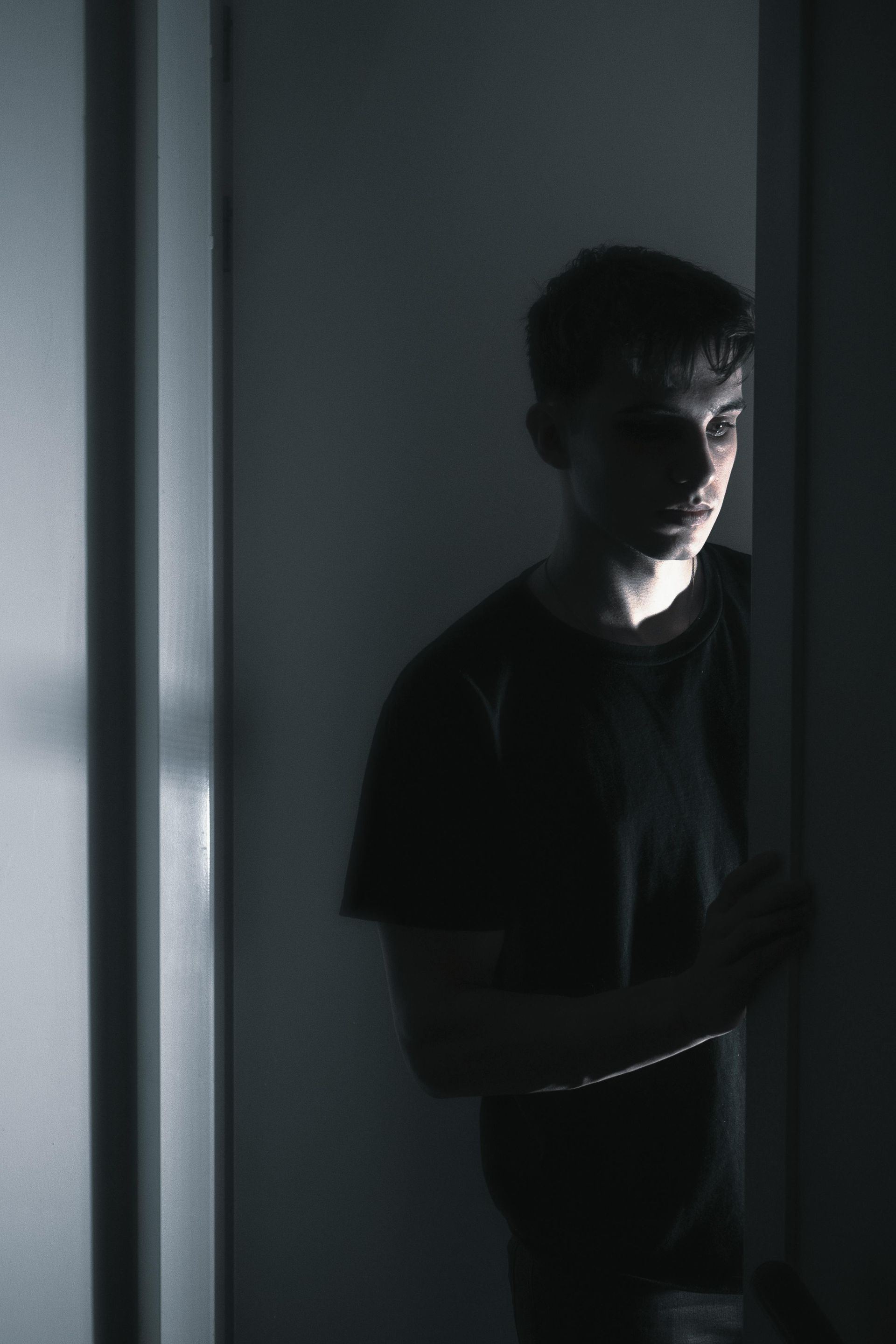 A man in a black shirt is standing in a dark room.