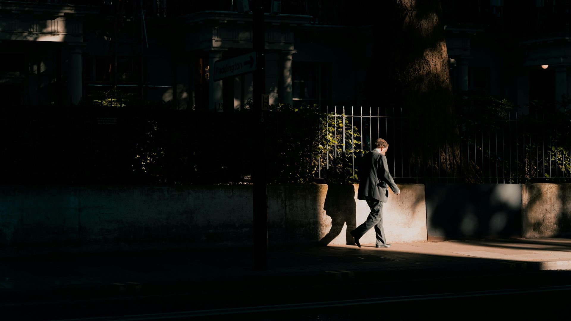 Man walking down a street in the dark with light shining on him 