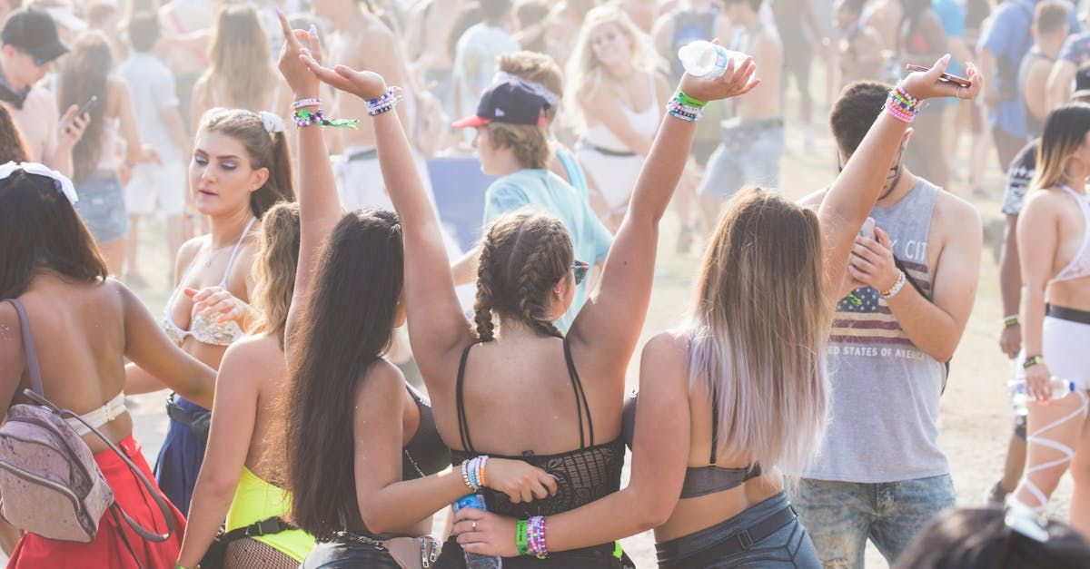 A group of people are dancing at a music festival with their arms in the air.