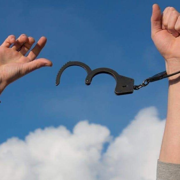 A person is holding a pair of handcuffs in their hands.