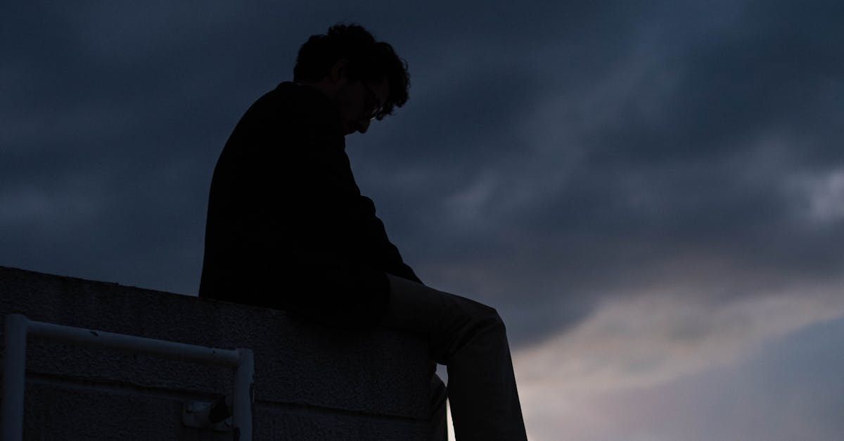 A man is sitting on the edge of a building at night.