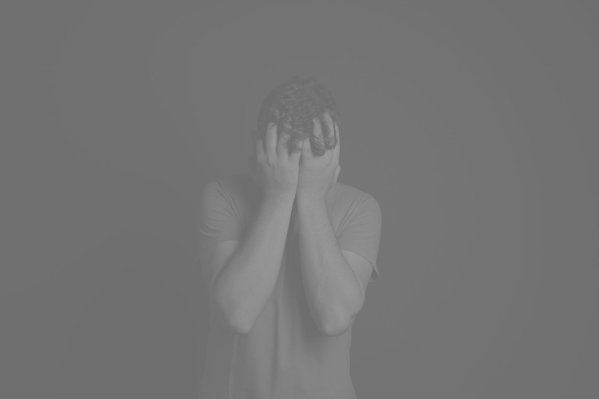 Black and white picture of ashamed man with head in hands