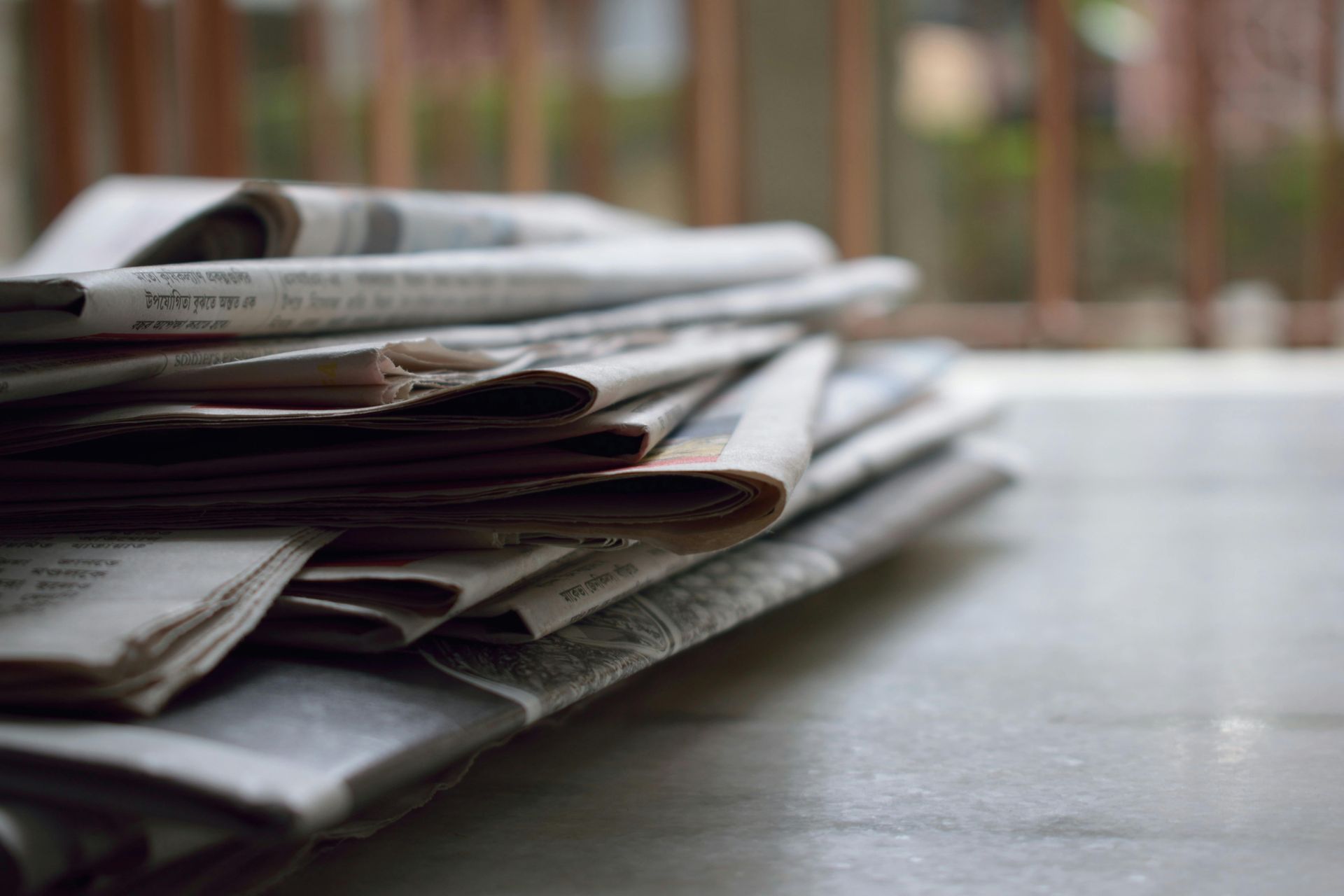 Desk with newspapers piled upon it. 