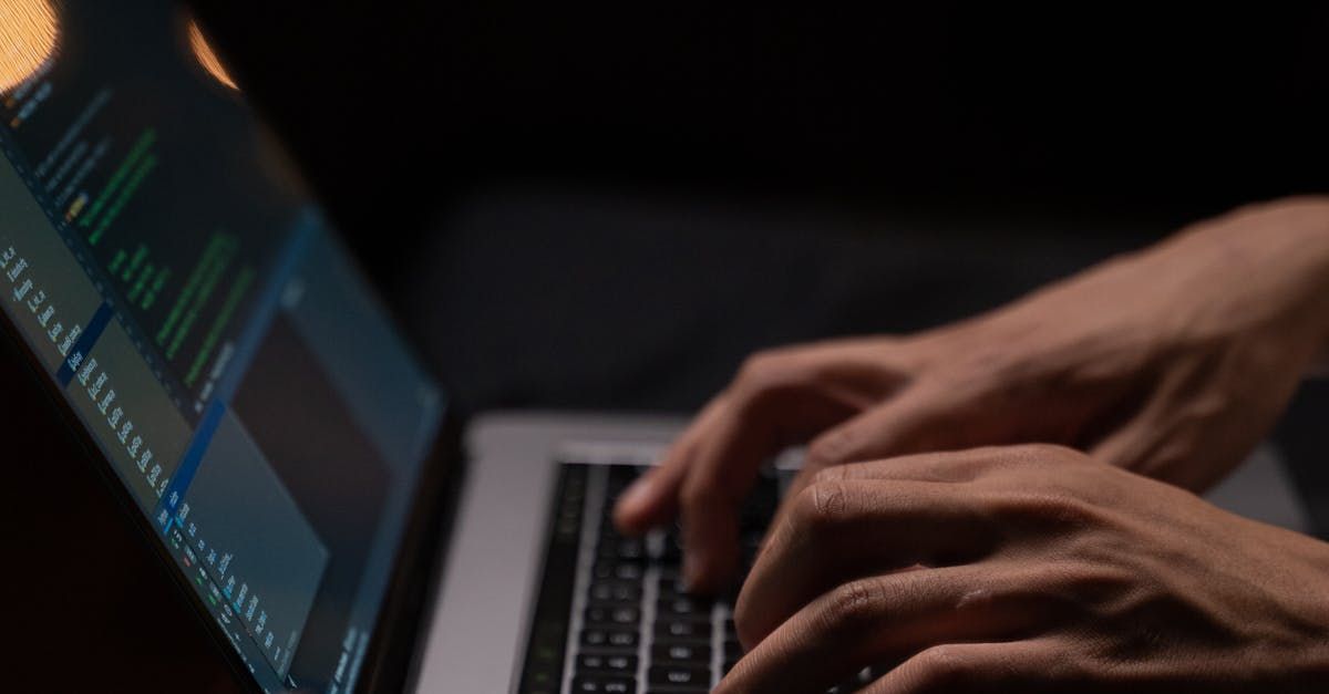 A person is typing on a laptop computer in a dark room.