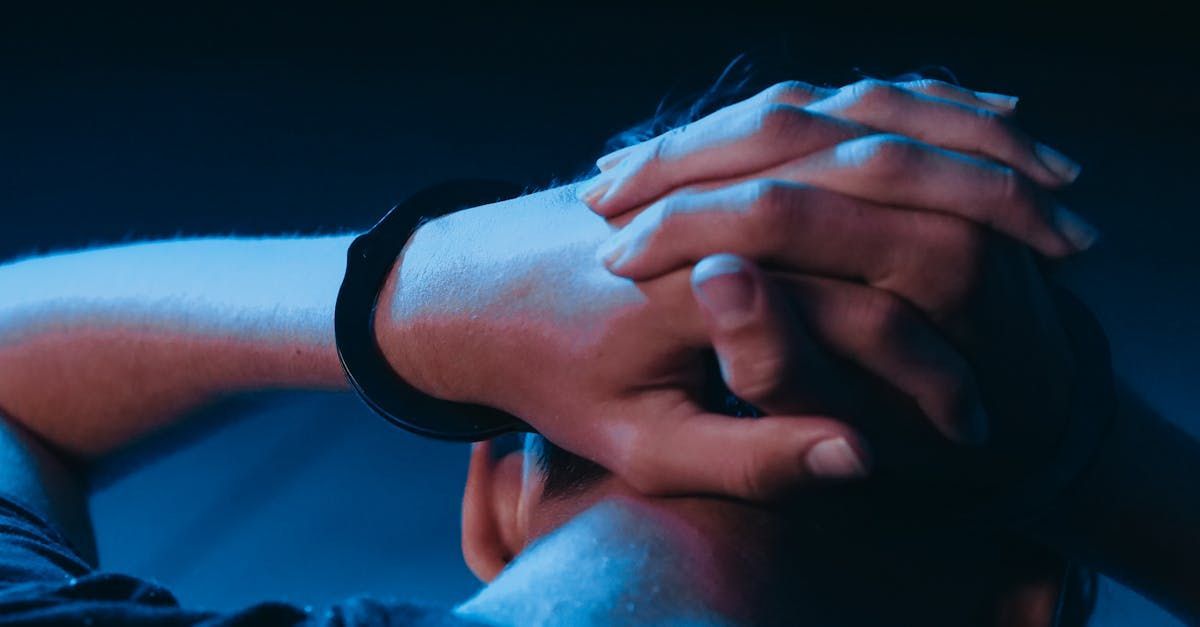 A person is praying with their hands folded over their head.