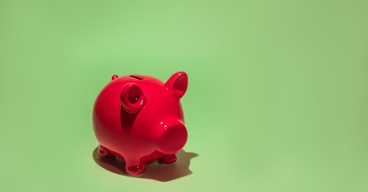 A red piggy bank is sitting on a green surface.