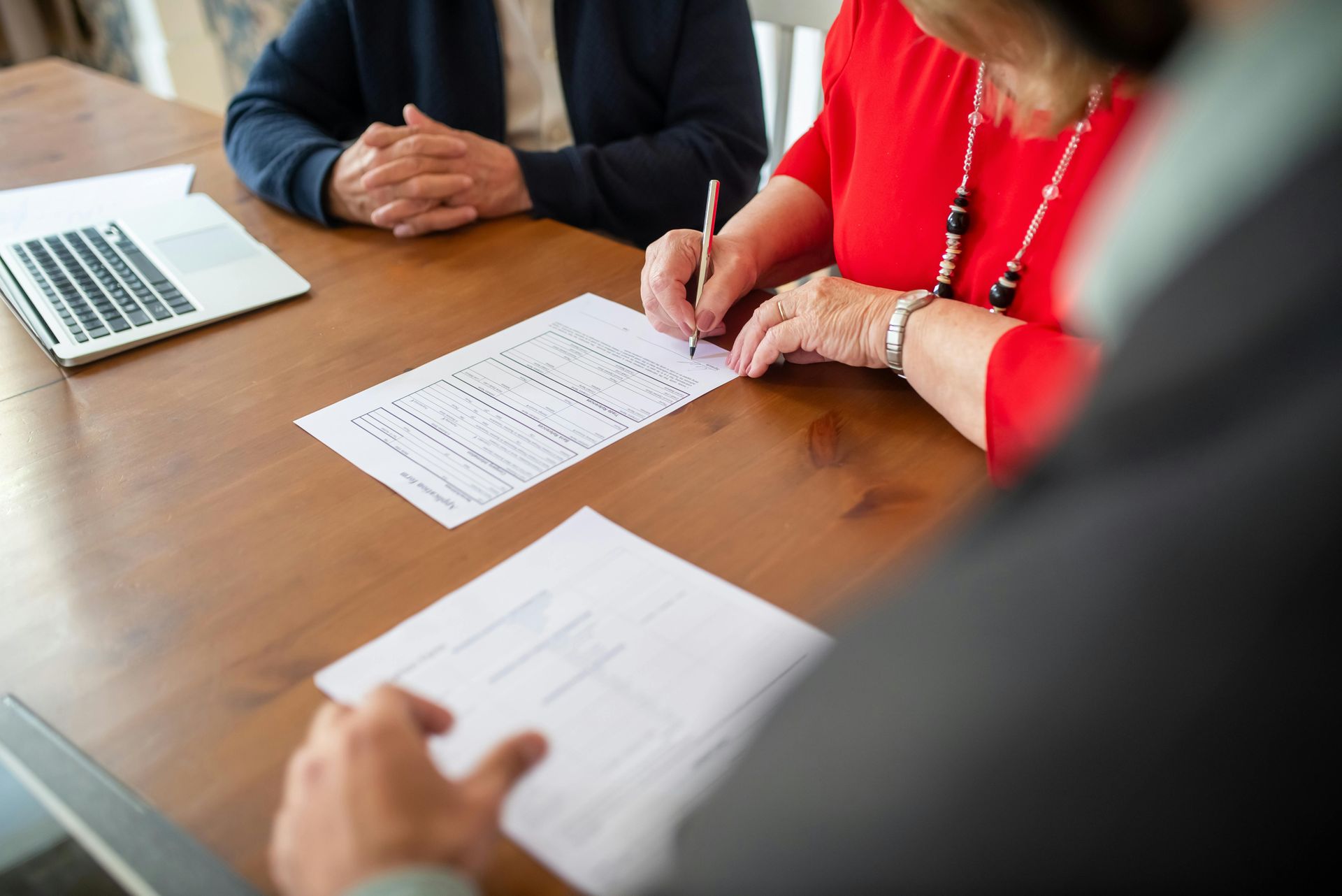 3 people sat around desk signing forms