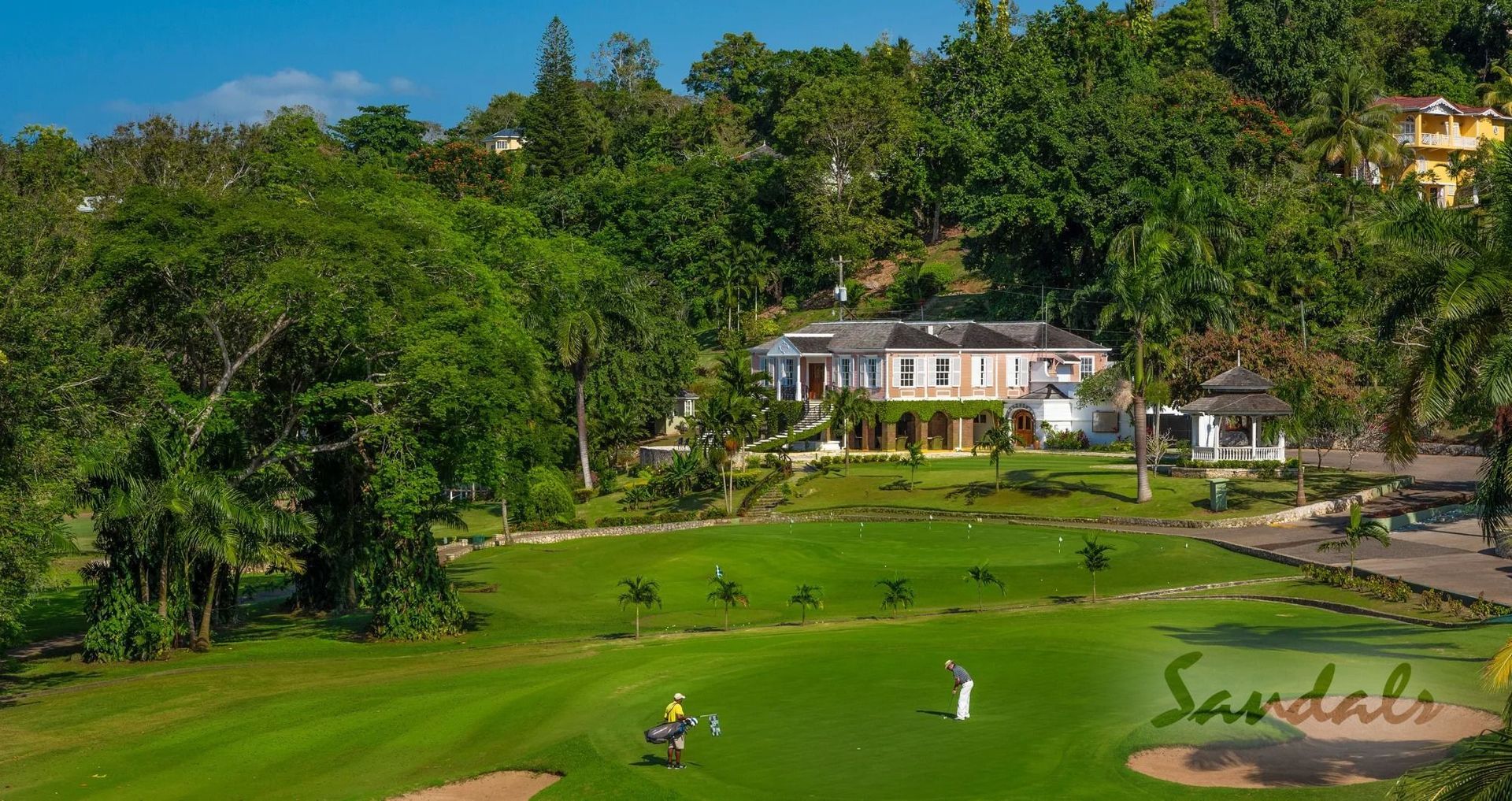 A golfer putts on a green in the foreground with the Upton Golf and Country Club clubhouse in the background.