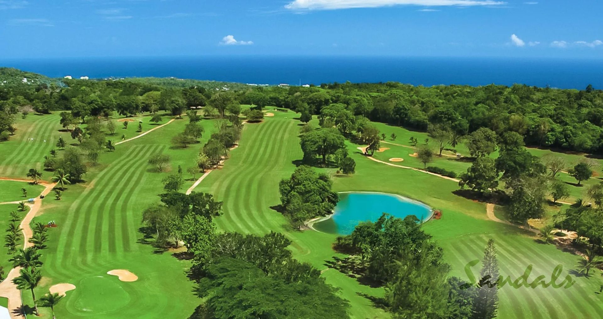 Aerial view to lush green, manicured fairways with the Atlantic Ocean in the distance at Upton Country Club.