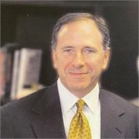 Smiling man in a suit and tie, likely in an office setting.