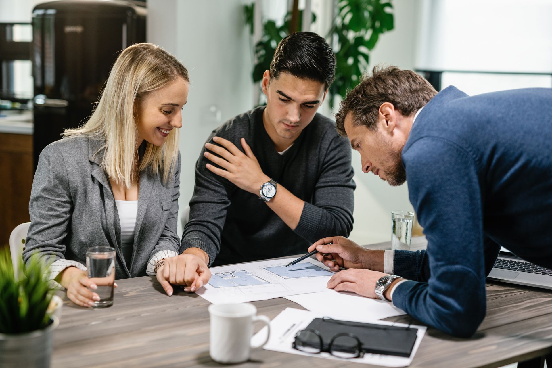 A couple reviews paperwork with a financial advisor at a table, discussing finances.
