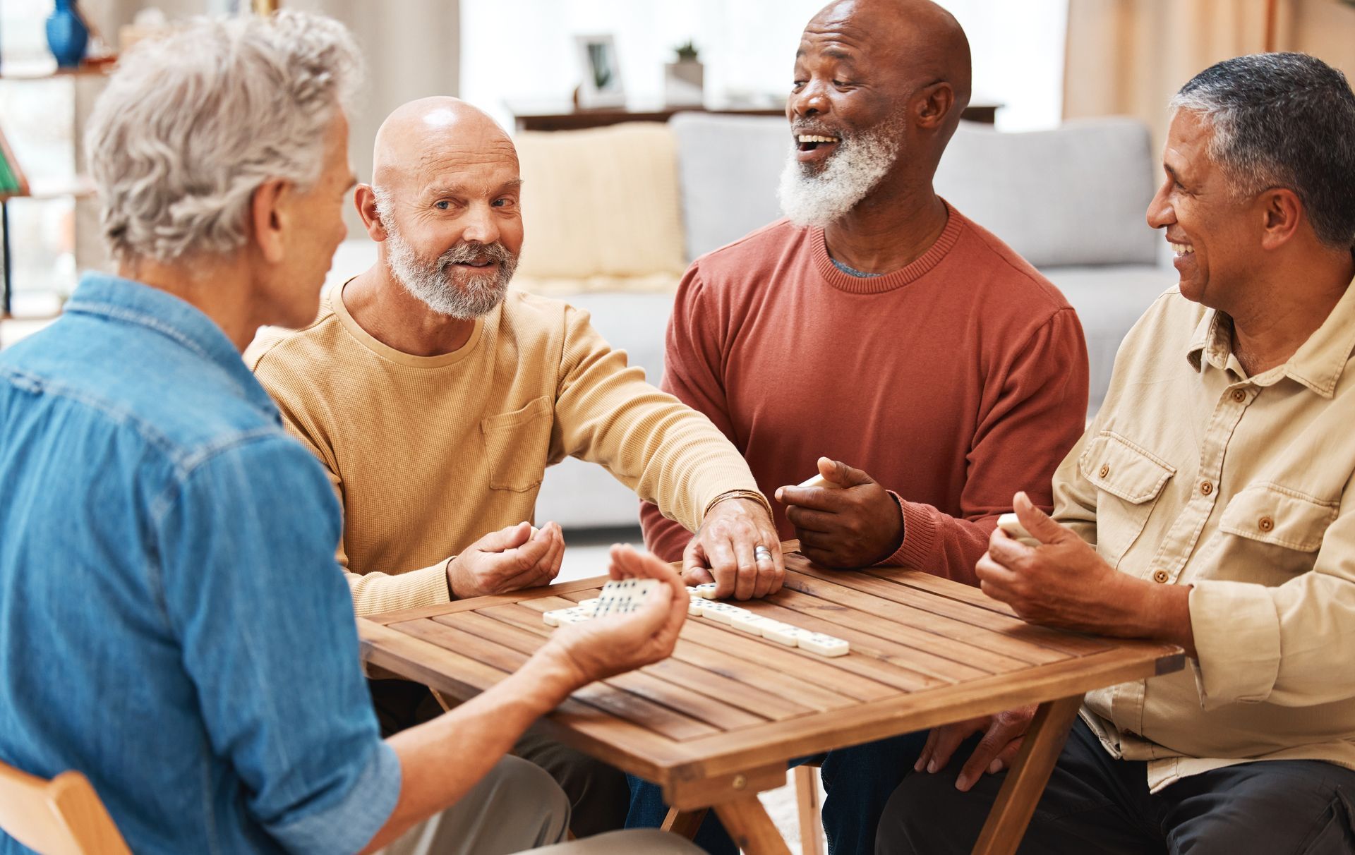 Four people toasting drinks at a table. They're smiling in a coffee shop with a sunny background.