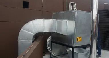 Un hombre está parado junto a una tubería de metal en una habitación.