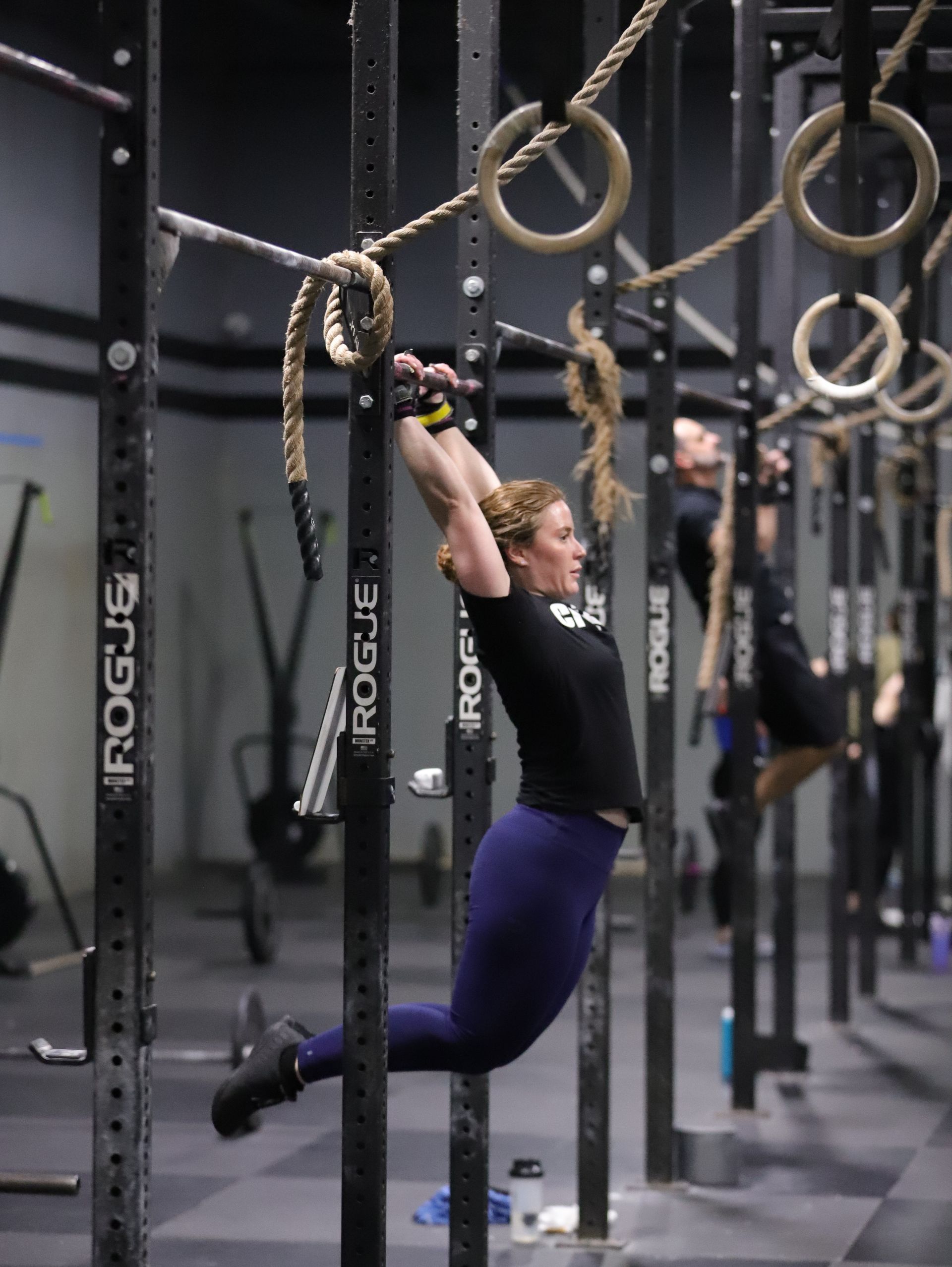 A woman performs a kipping pull up.