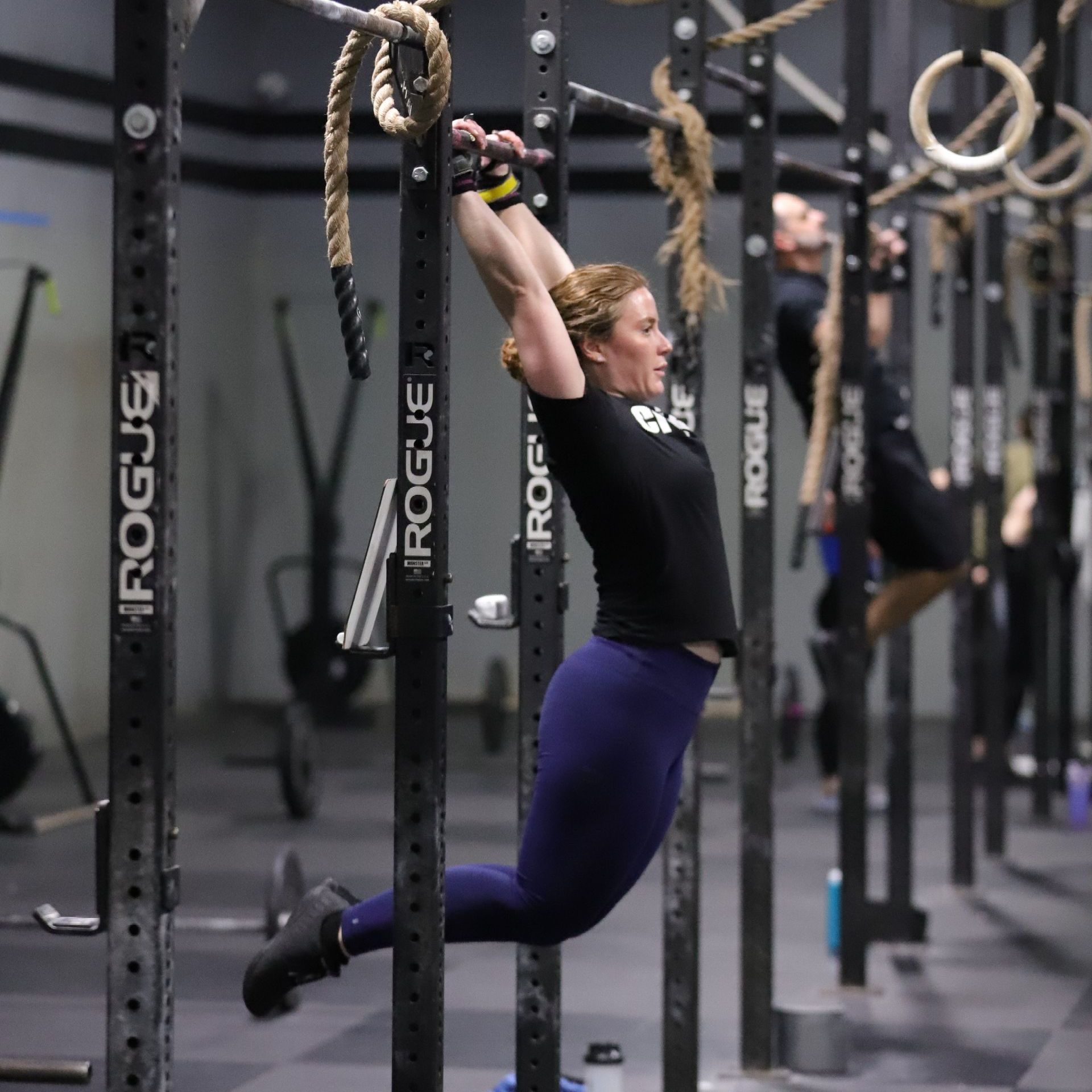 A woman performs a kipping pull up.