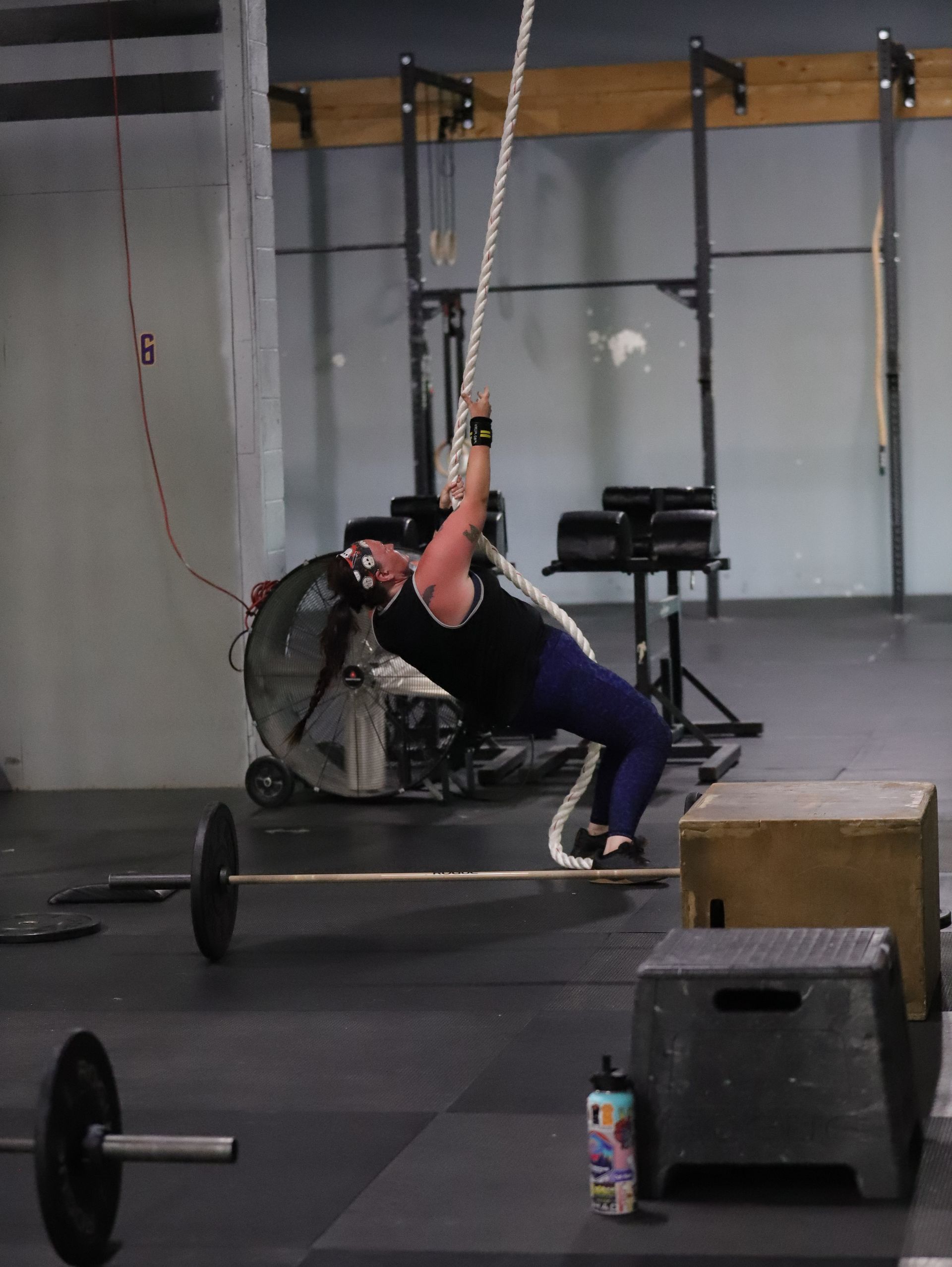 A woman performs a rope climb.