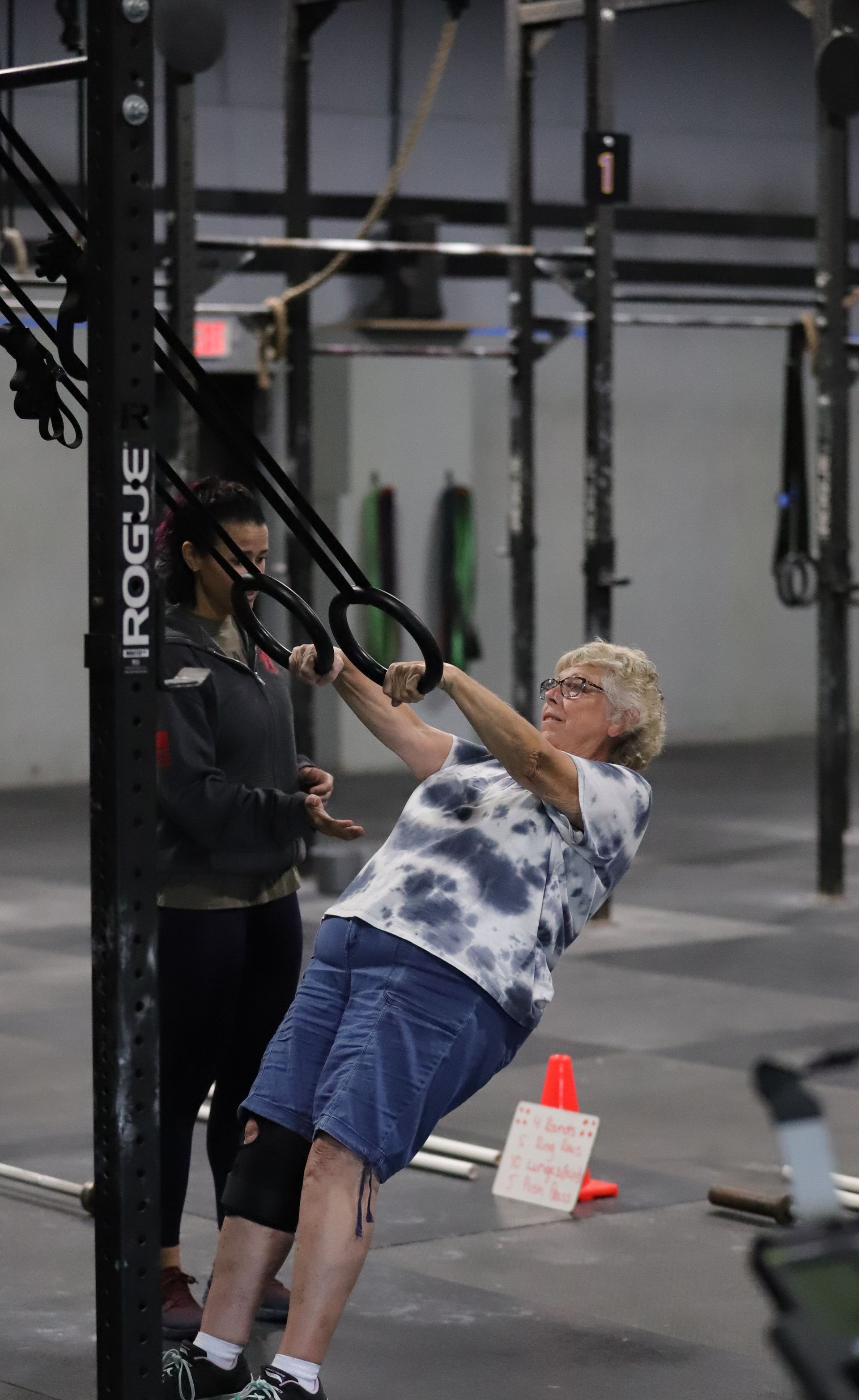 A woman coaching another woman through the ring row.