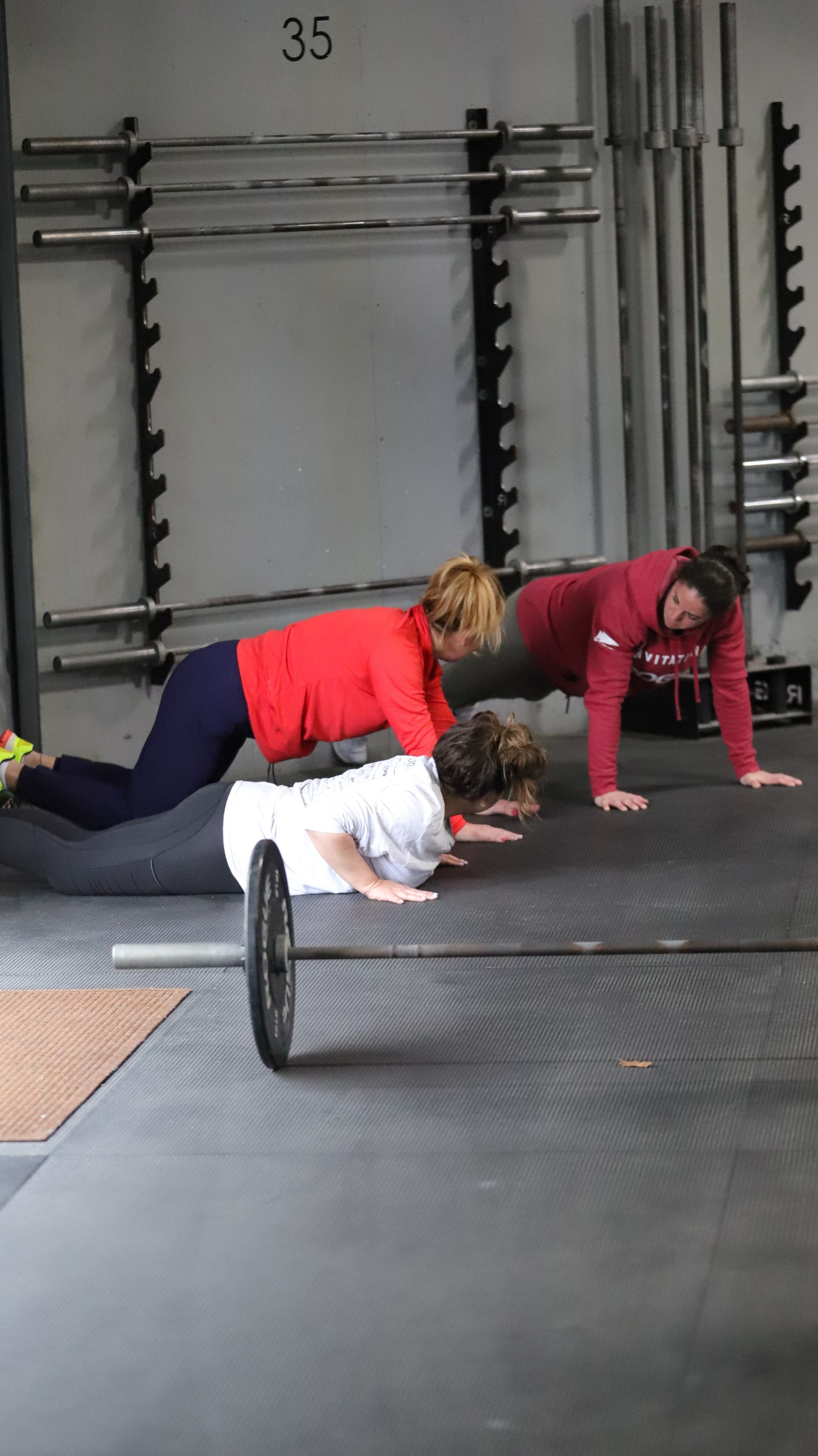 A coach is guiding gym members through the push up