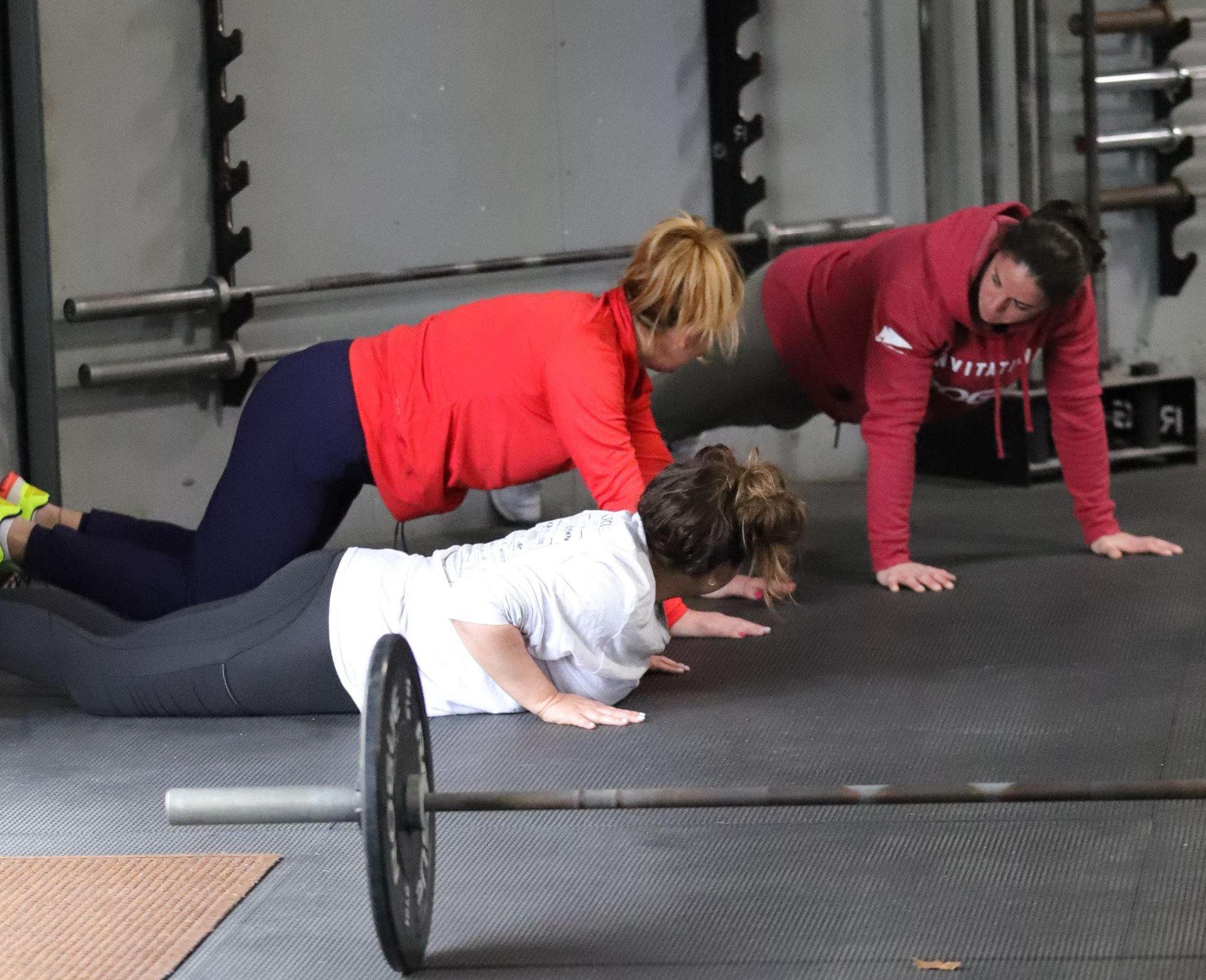 A coach guides gym members through the push up