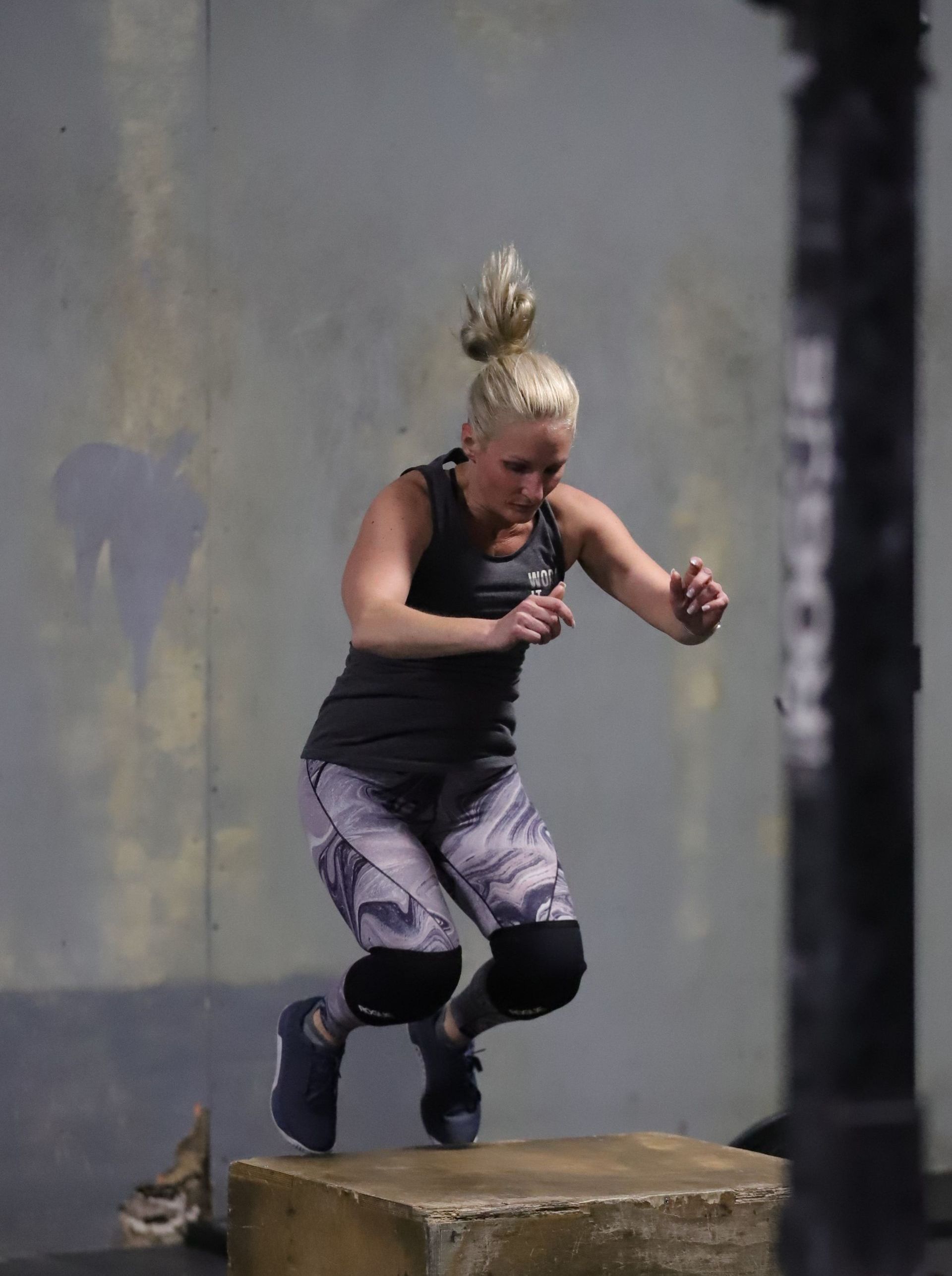 A woman jumps on a box.