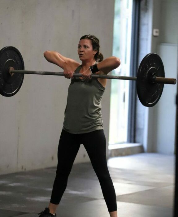 A woman performs a barbell movement.