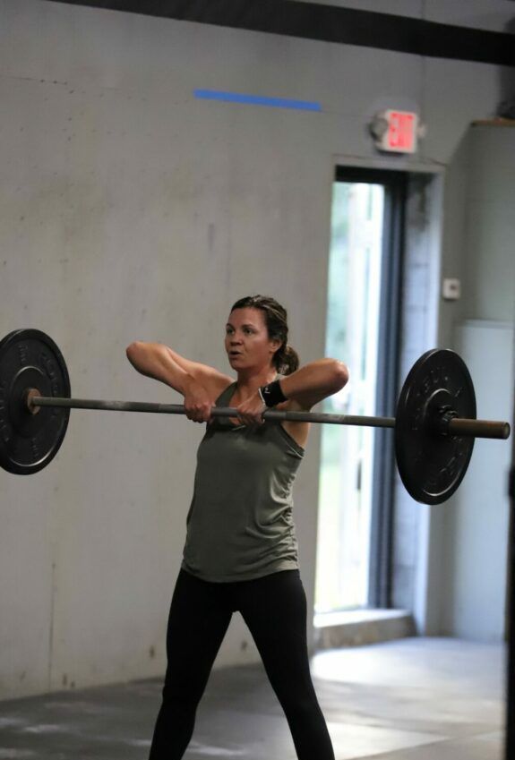 A woman performs a barbell movement.