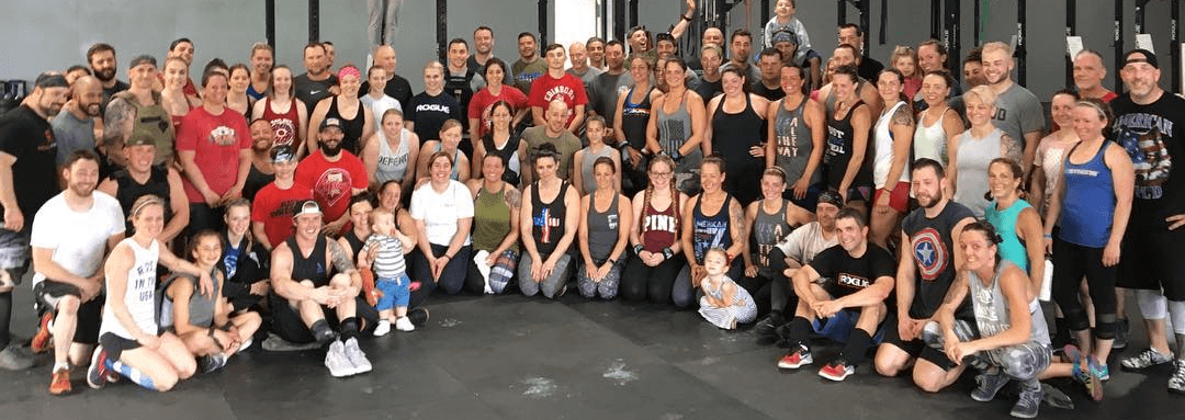 A large group of gym members of CrossFit Vertex are posing for a picture in the gym.