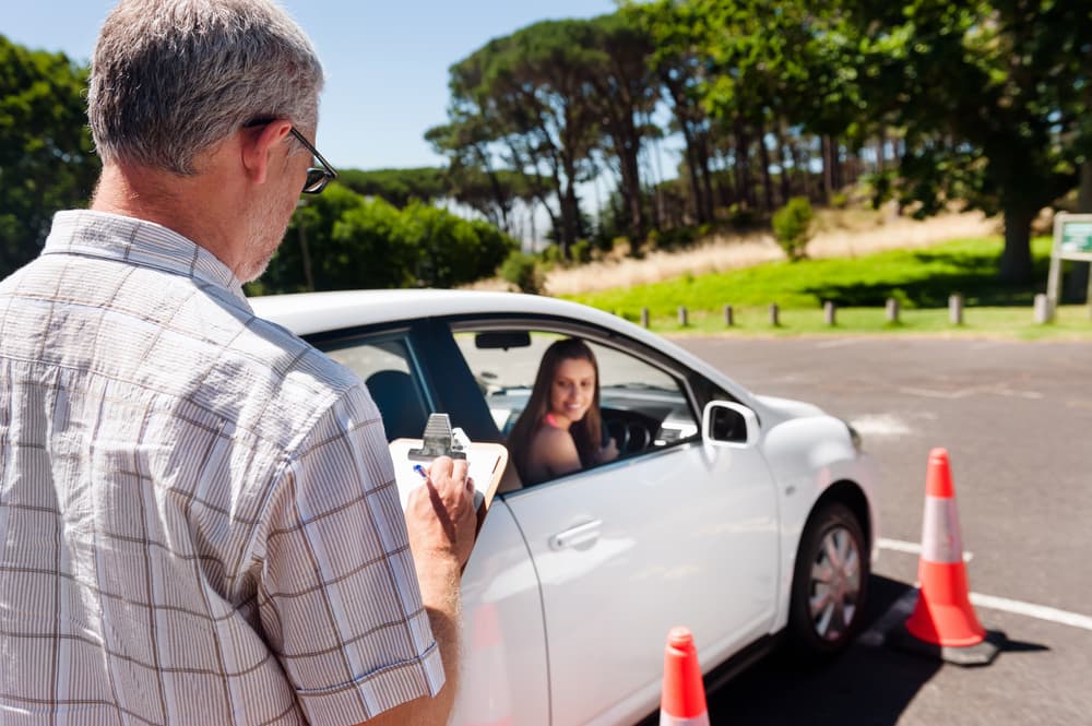 A Man is Writing on a Piece of Paper While a Woman is Driving a Car — NT Driving Academy in Woolner, NT