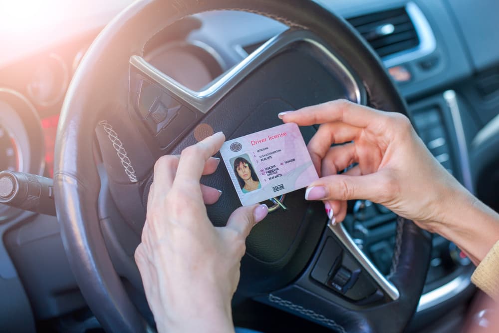 A Woman is Holding a Driving License in Her Hands While Sitting in a Car — NT Driving Academy in Woolner, NT