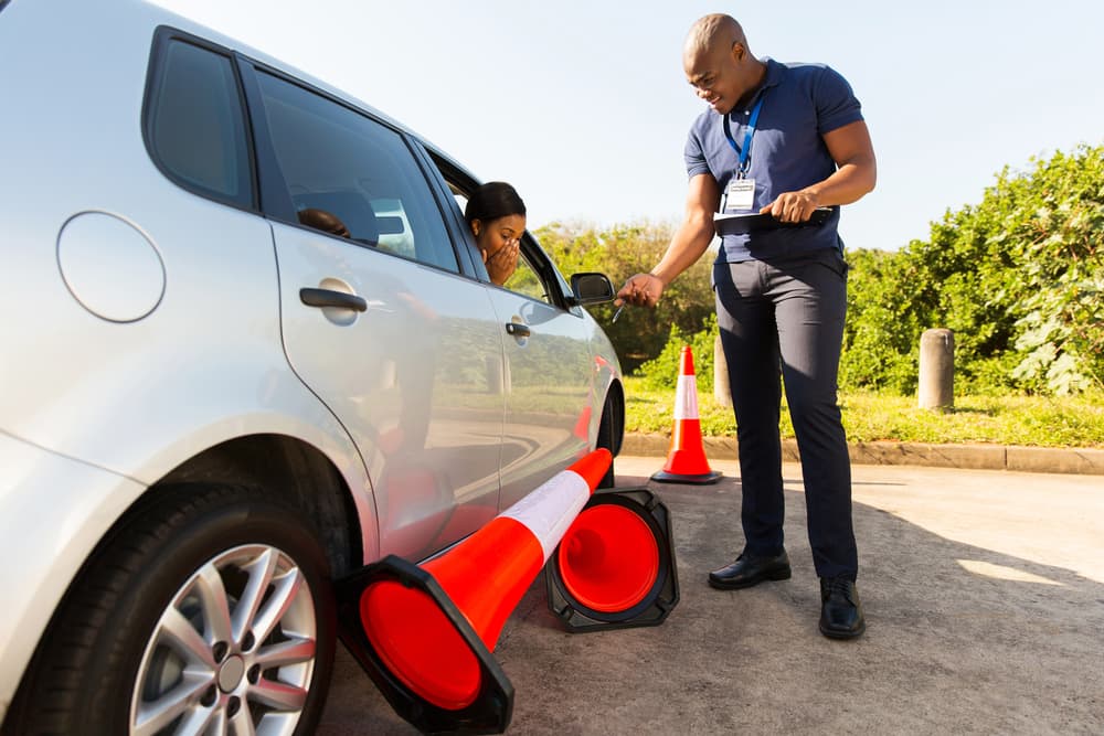 A Man is Standing Next to a Car With a Broken Tire — NT Driving Academy in Woolner, NT