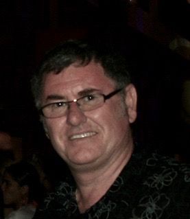 A Man Wearing Glasses and a Black Shirt is Smiling for the Camera — NT Driving Academy in Woolner, NT