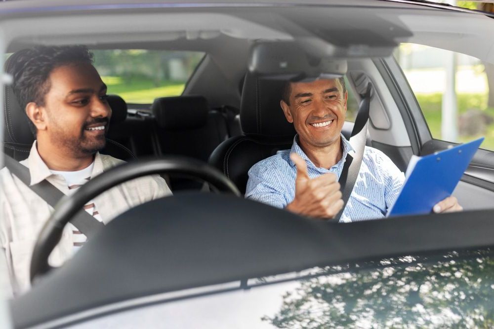 A Man is Giving a Thumbs Up While Sitting in a Car With Another Man — NT Driving Academy in Casuarina, NT