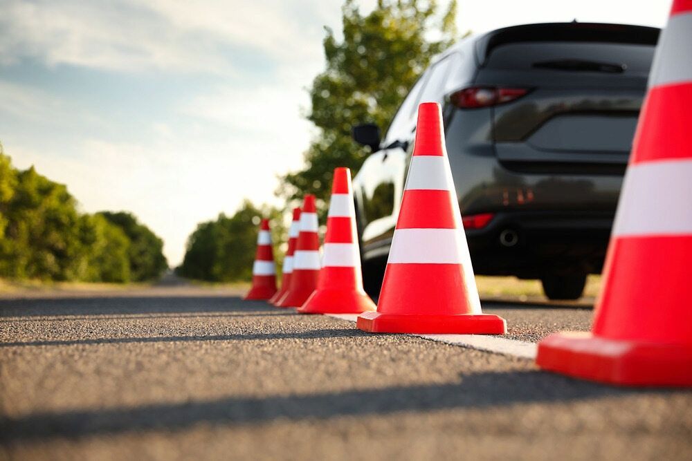 A Row of Traffic Cones on the Side of a Road Next to a Car — NT Driving Academy in Woolner, NT