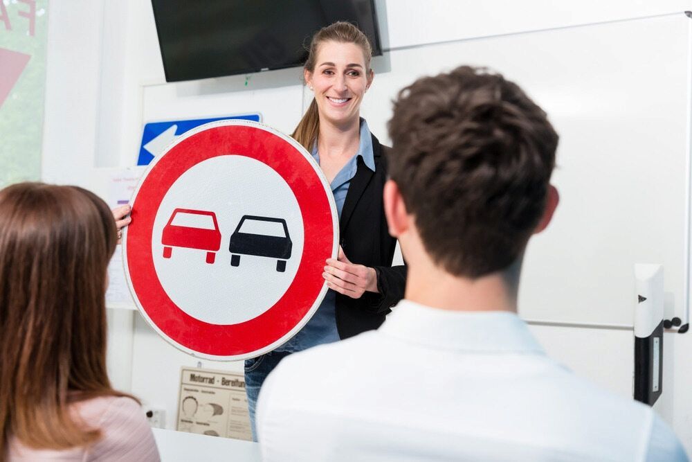 A Woman is Holding a Sign in Front of a Group of People — NT Driving Academy in Palmerston, NT