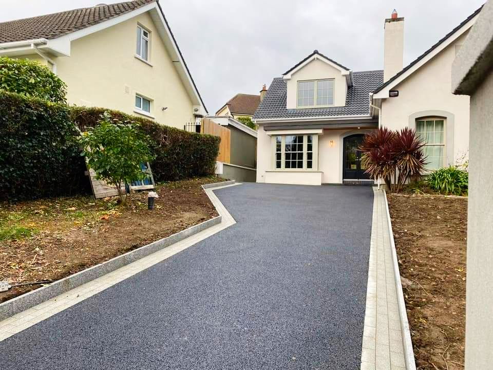 A white house with a black driveway leading to it