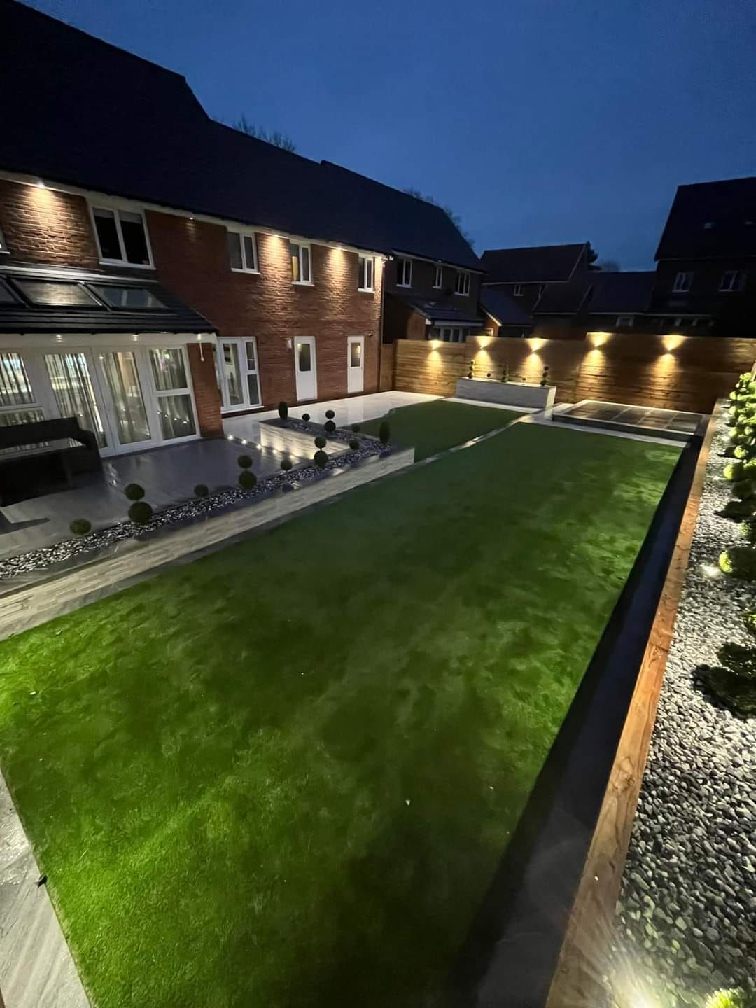 A house with a large lawn in front of it at night.