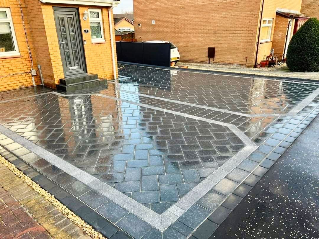 A brick driveway is being built in front of a house.