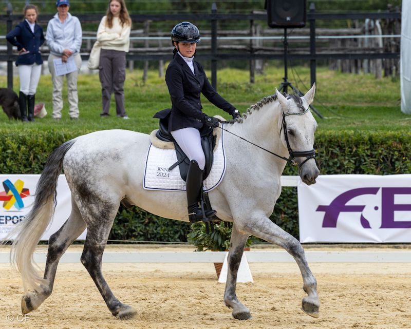 A woman is riding on the back of a gray horse.