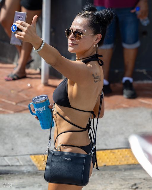 A woman in a bikini is taking a selfie with her phone